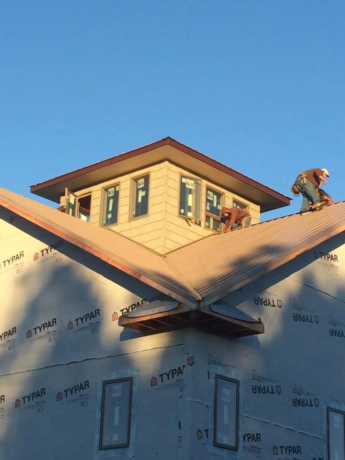 Roofers working around a rooftop cupola on a new metal roof at sunset — Roof Waterproofing in Canton by Roofing Brothers